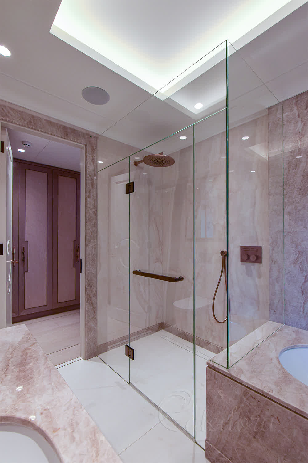 Frameless luxury shower enclosure with antique copper fixtures in a marble bathroom