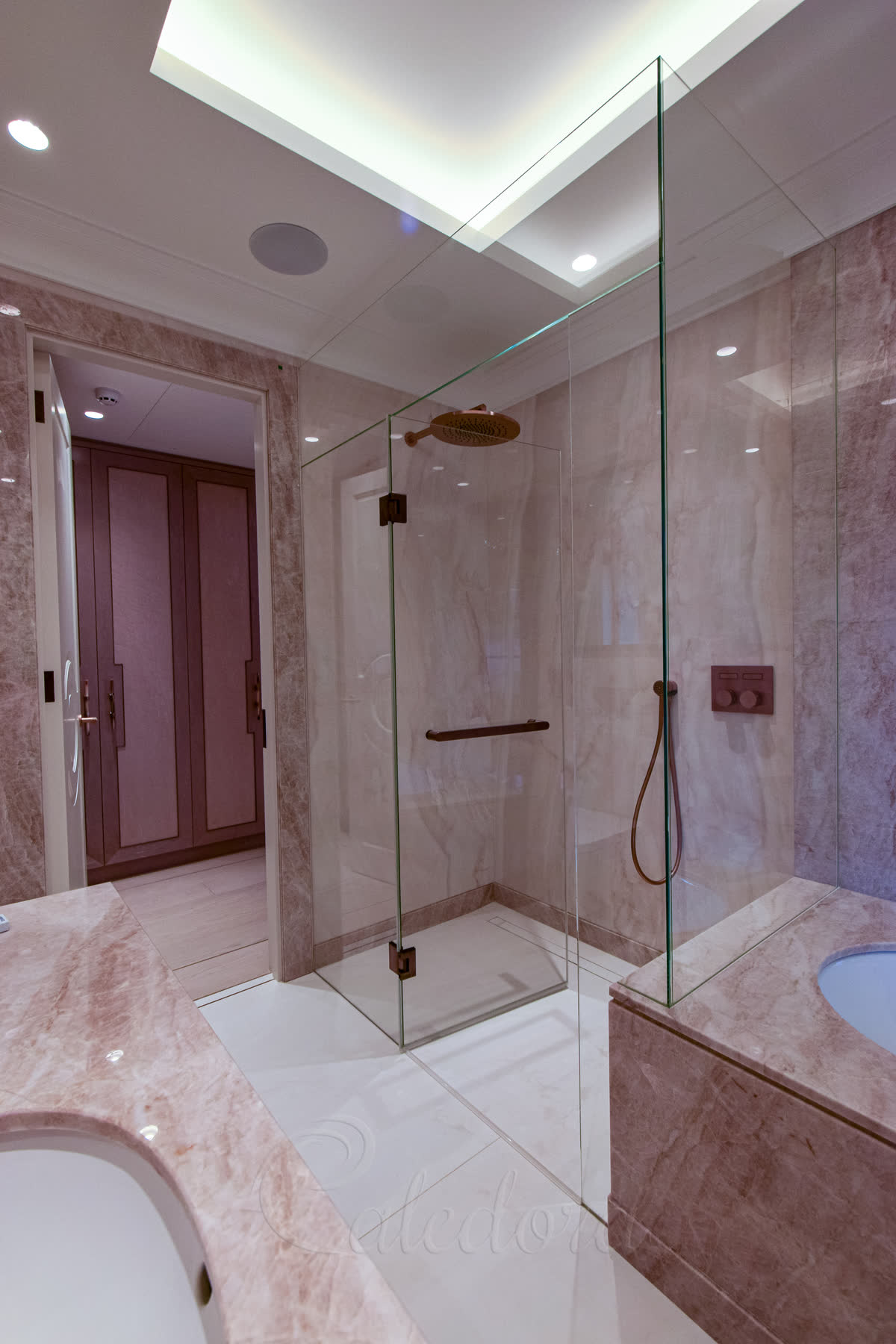 Interior view of frameless shower enclosure with copper fixtures and wall-recessed panels