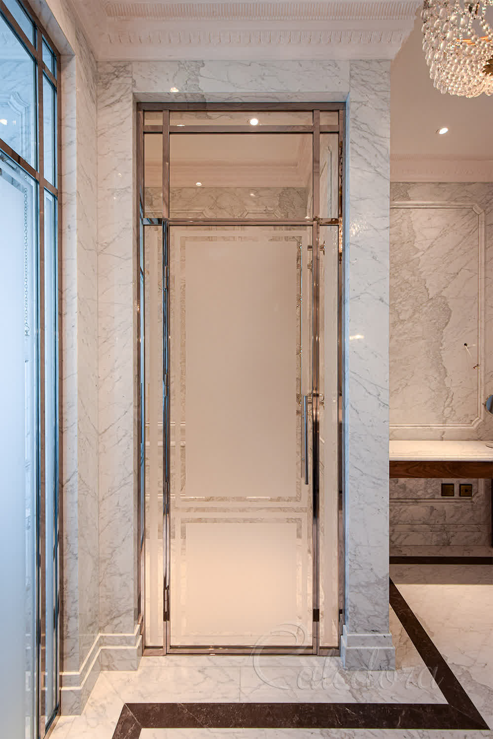 Luxury framed nickel shower door with sandblasted glass panels and polished metal frame in marble bathroom