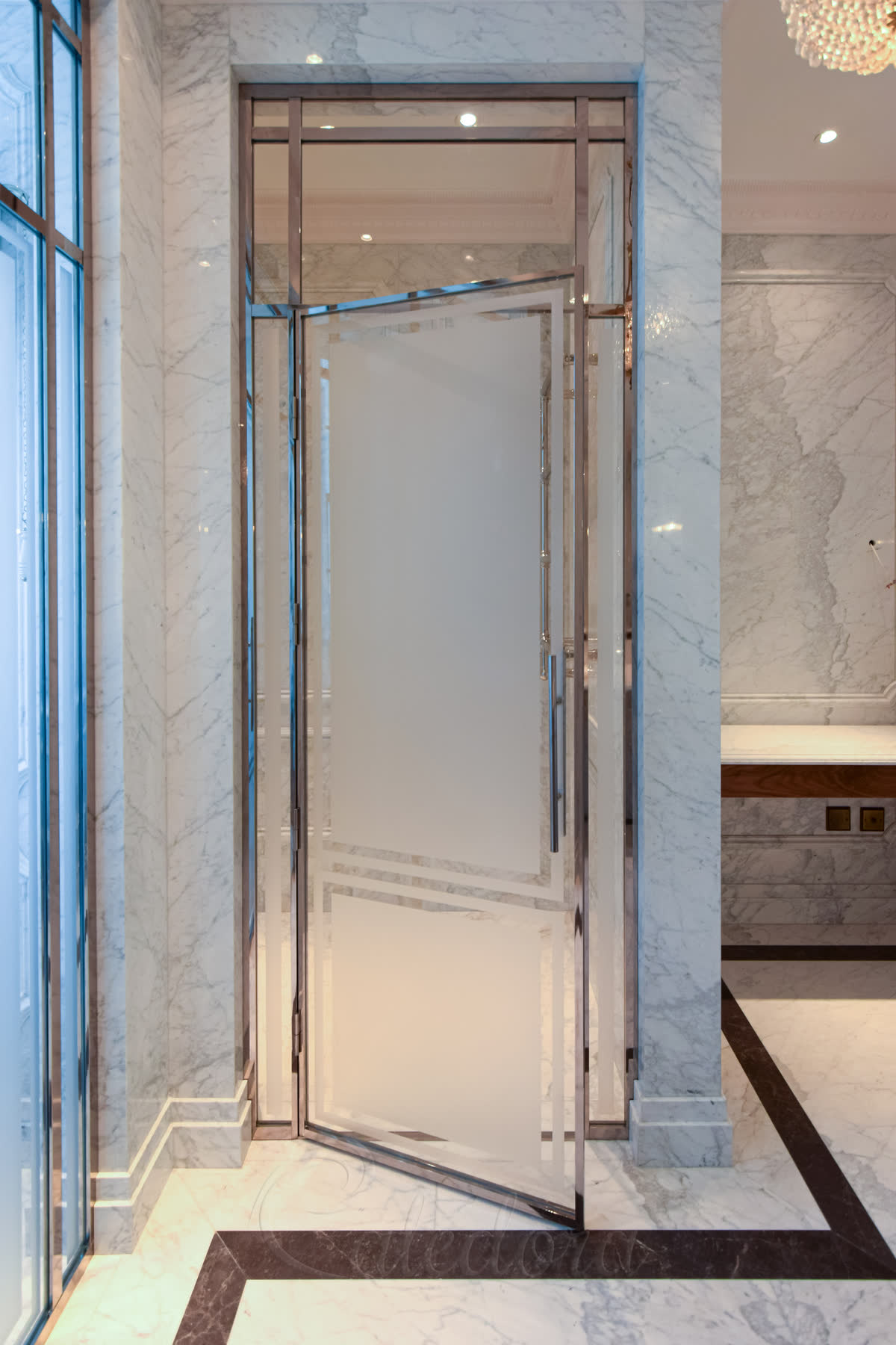 Open nickel-framed shower door showing the interior marble shower space and ladder-style handle