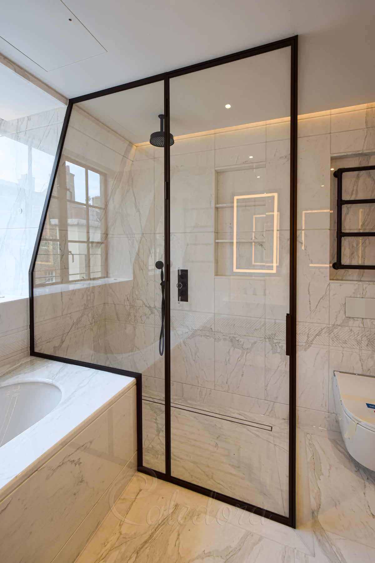 Dark bronze shower frame following the slope of the ceiling with ultra clear glass panels