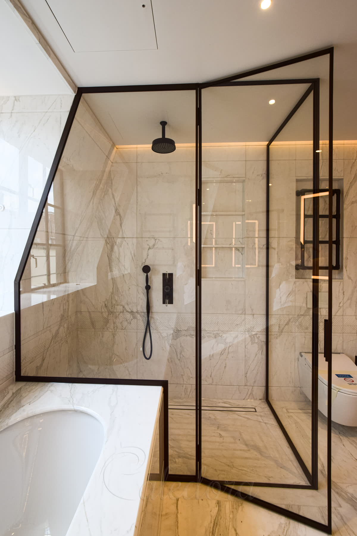 Close-up view of the custom bronze frame and precisely cut glass fitting around the bath edge