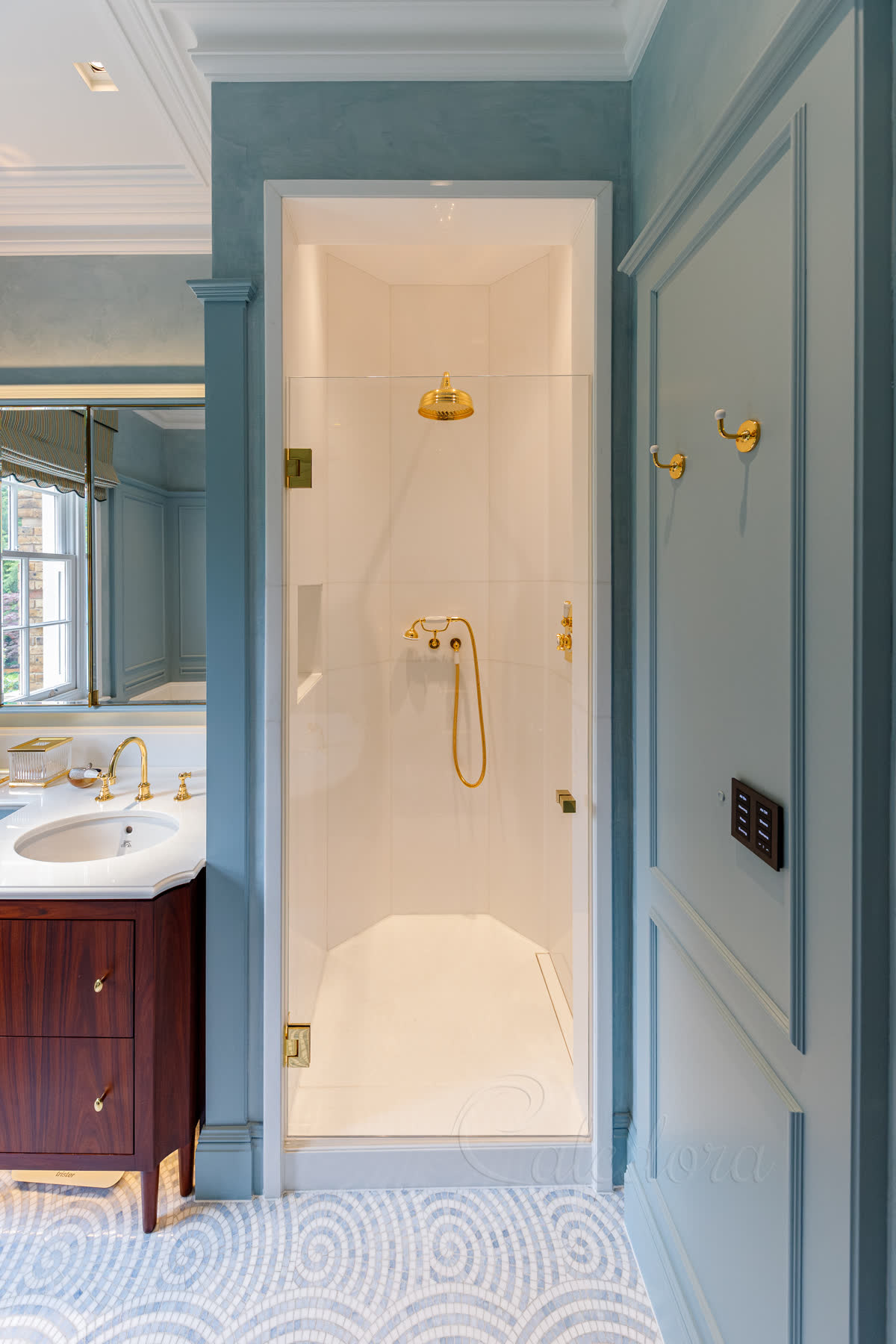 Polished brass hinged shower door in closed position showing ultra clear glass and natural stone shower walls
