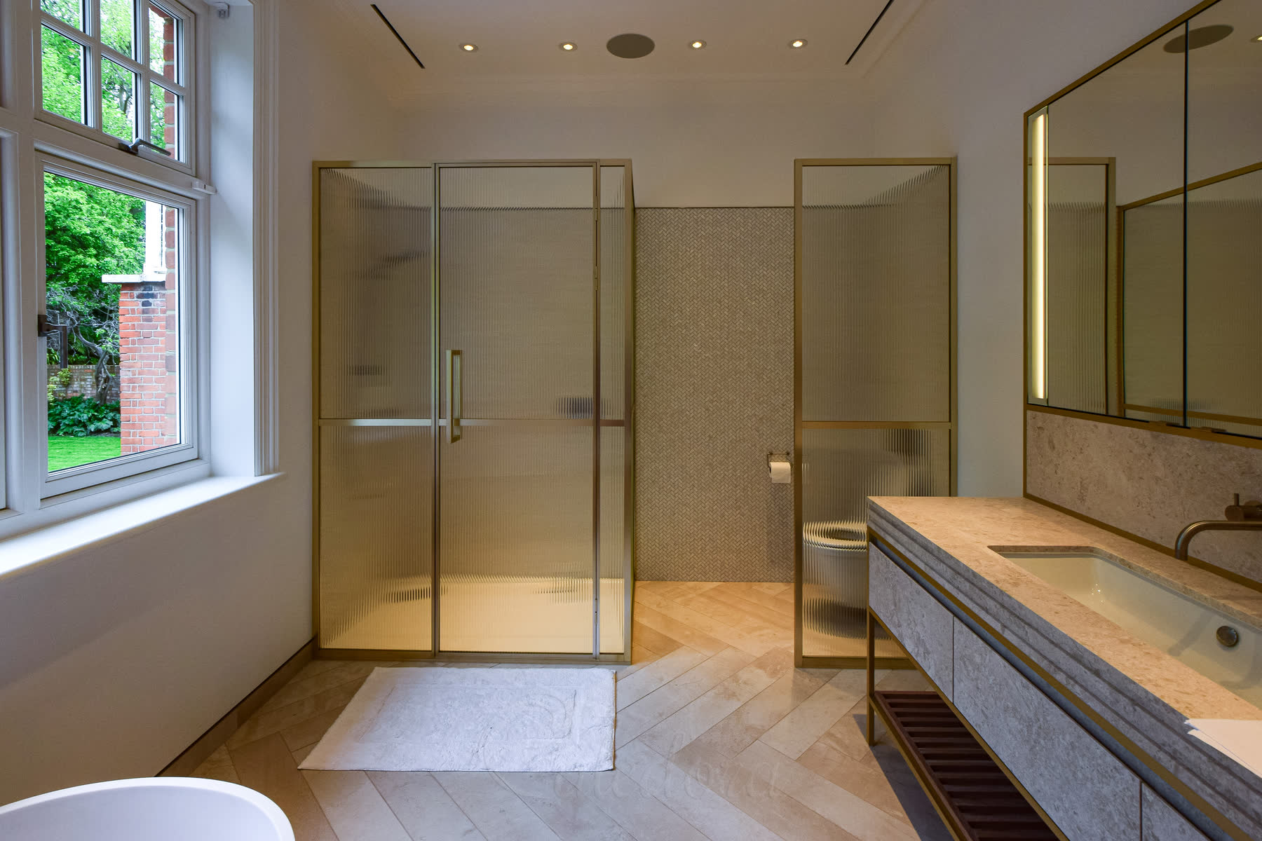 Coordinated bathroom design featuring bright gold shower enclosure and marble vanity unit