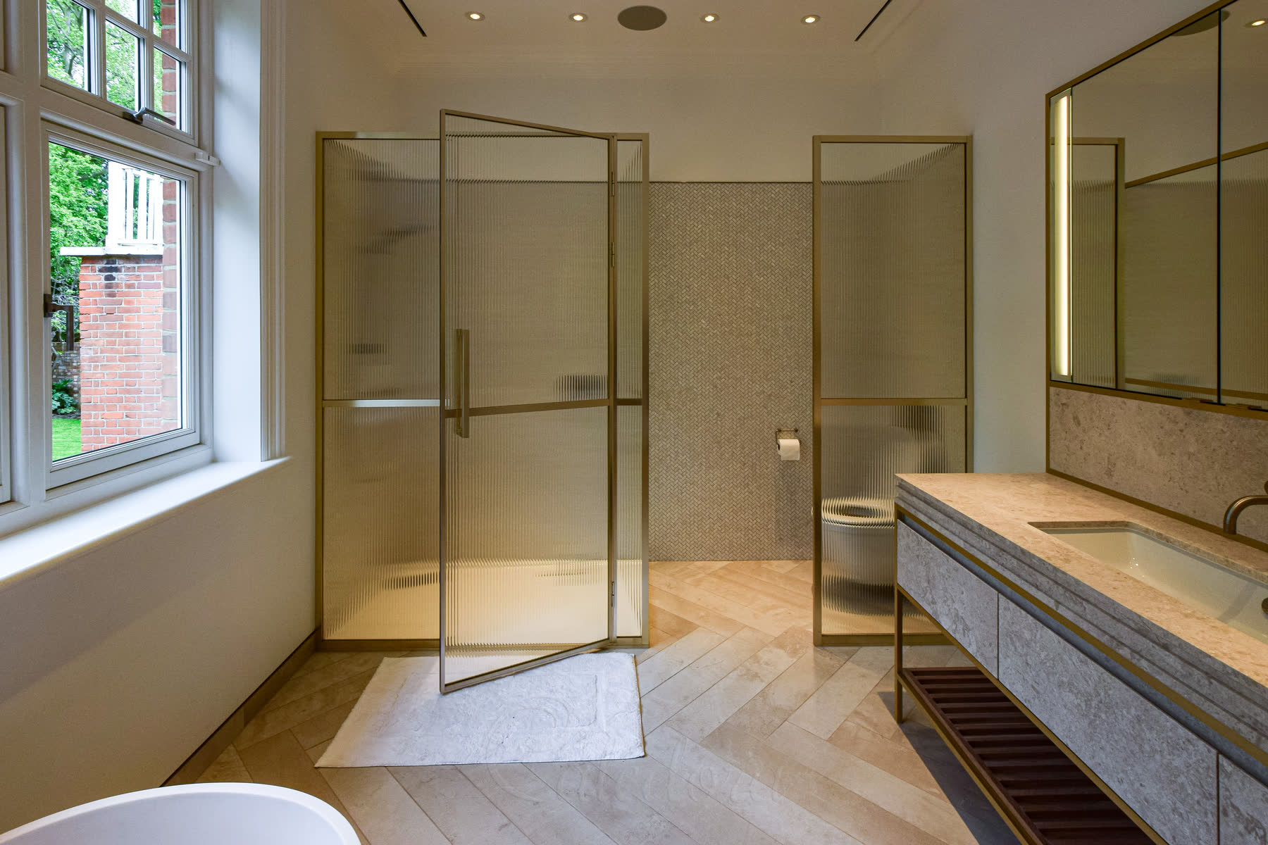 Wide view of luxury bathroom with light gold shower enclosure and door open