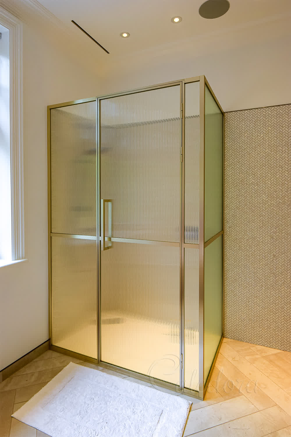 Luxury brass framed shower enclosure with reeded glass and bespoke handle in London bathroom
