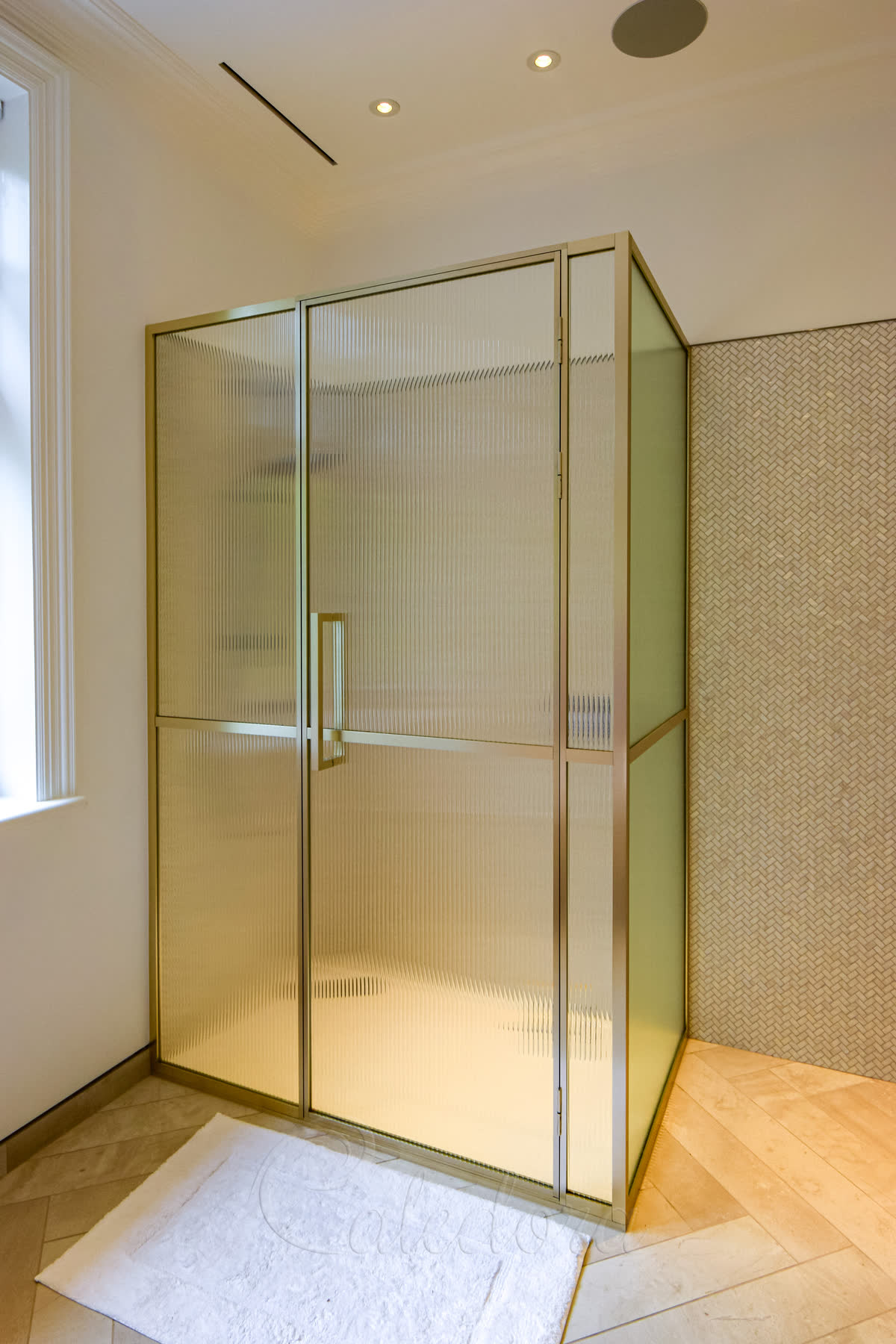 Luxury brass framed shower enclosure with reeded glass and bespoke handle in London bathroom