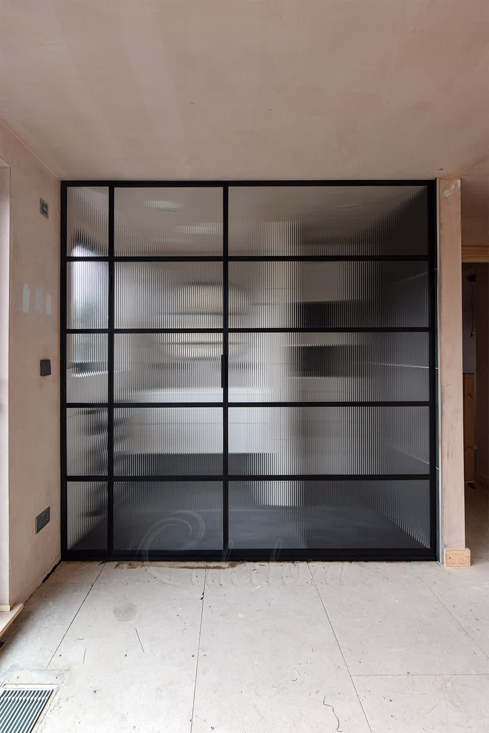 Black grid framed shower partition with ribbed glass panels providing privacy while allowing light in modern bathroom