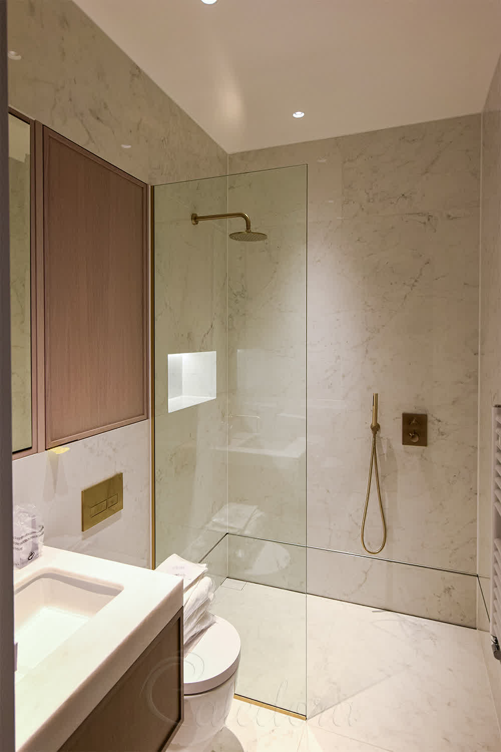 Short shower screen Cookham showing small glass panel with brass fixtures and marble tiles