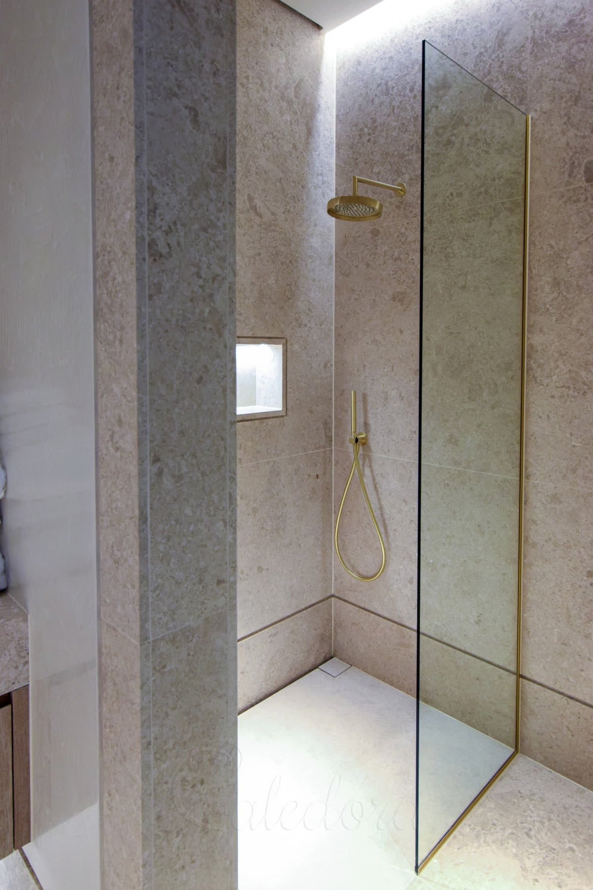 Walk-in shower with small glass screen demonstrating limited water protection coverage