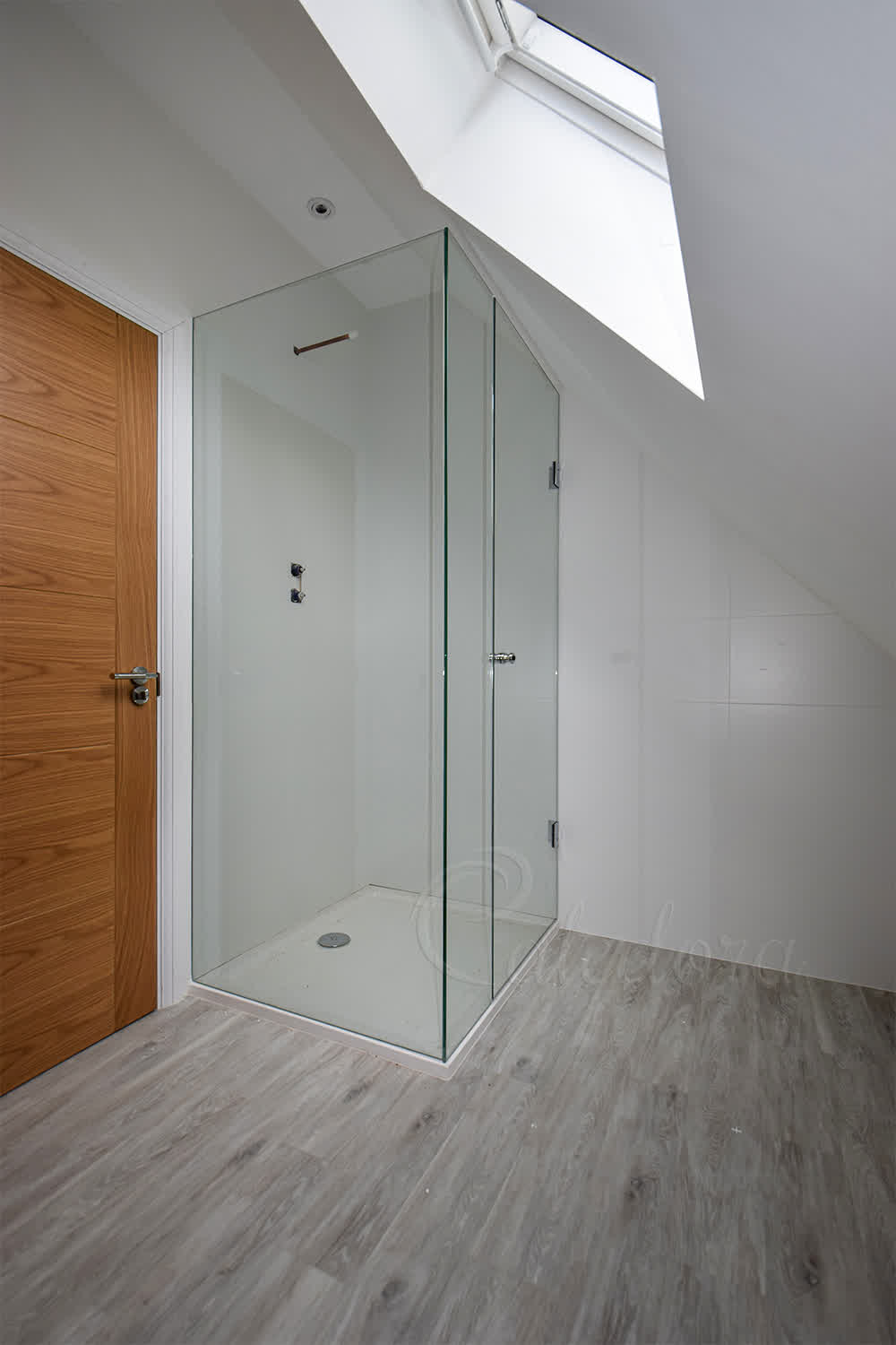 Frameless corner shower enclosure with hinged door under sloped ceiling in London