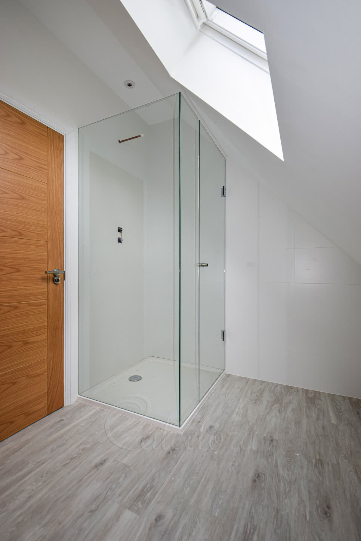Frameless corner shower enclosure with hinged door under sloped ceiling in London