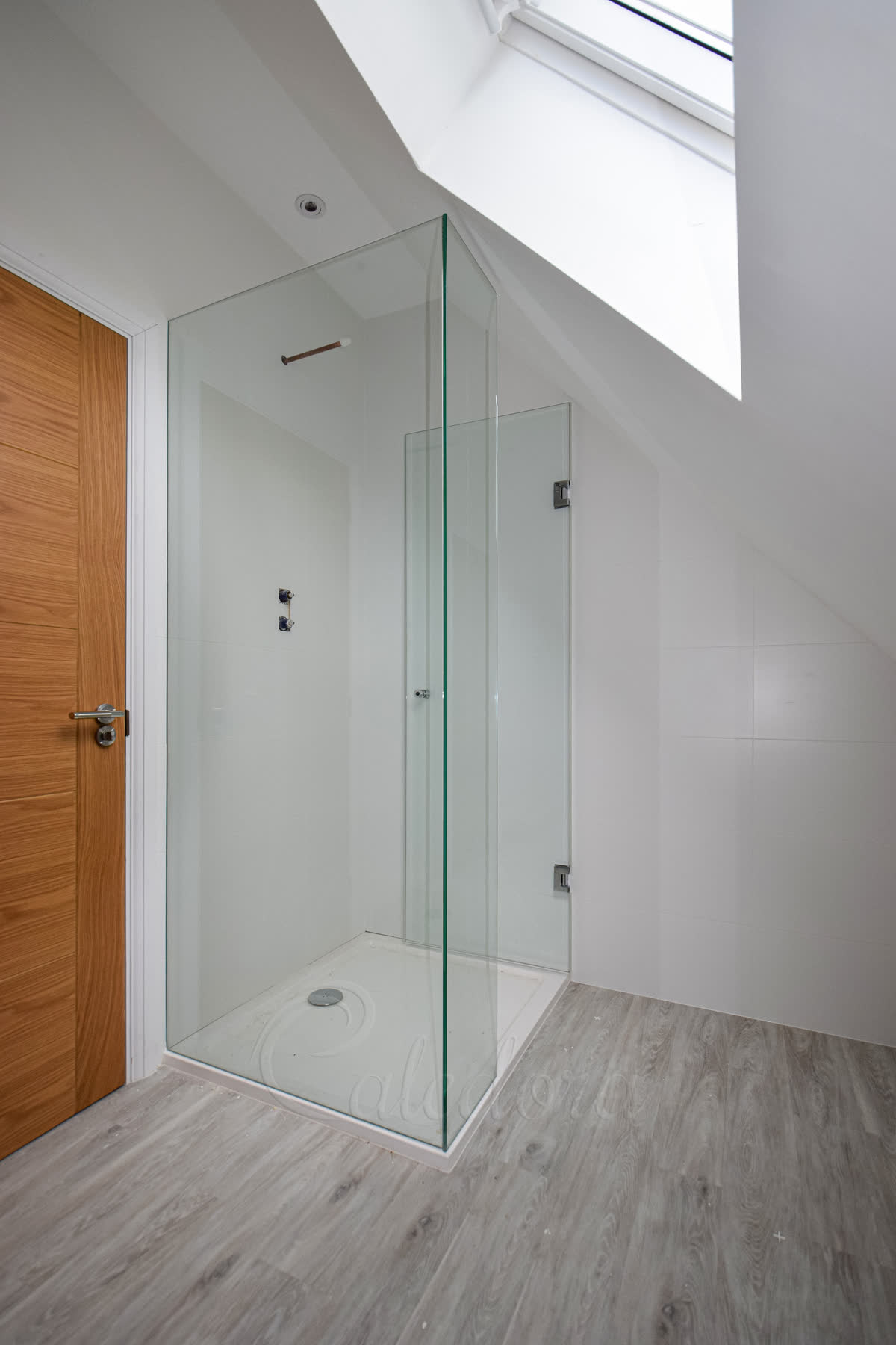 Shower enclosure with hinged door opened inwards showing chrome hinges