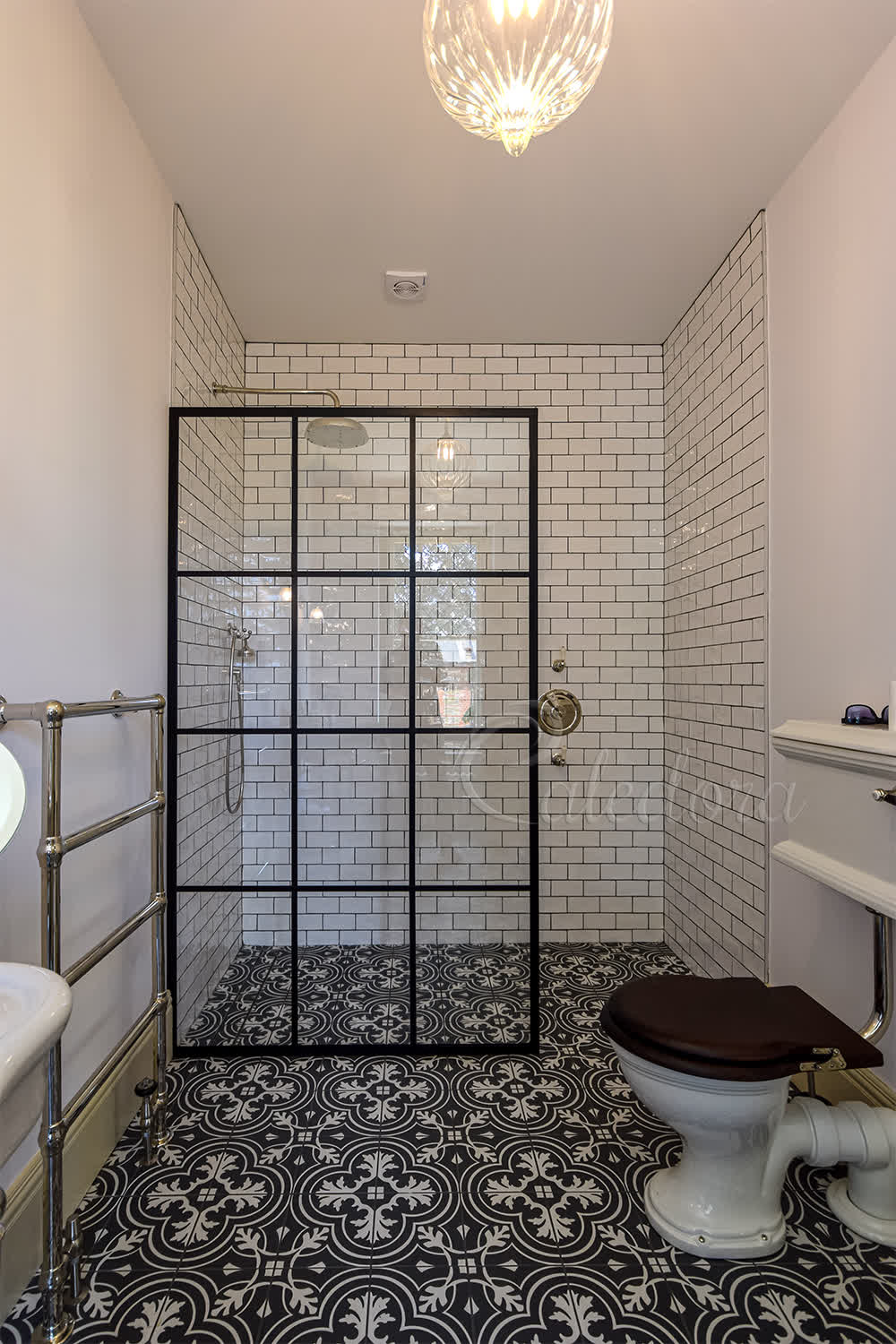 Black grid shower screen in London bathroom with beige subway tiles and patterned floor