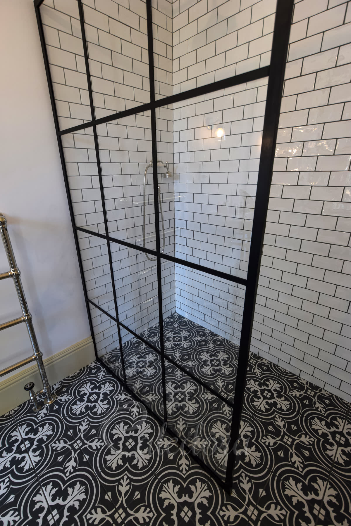 Corner view of black grid shower screen showing detailed frame pattern against beige subway tiles