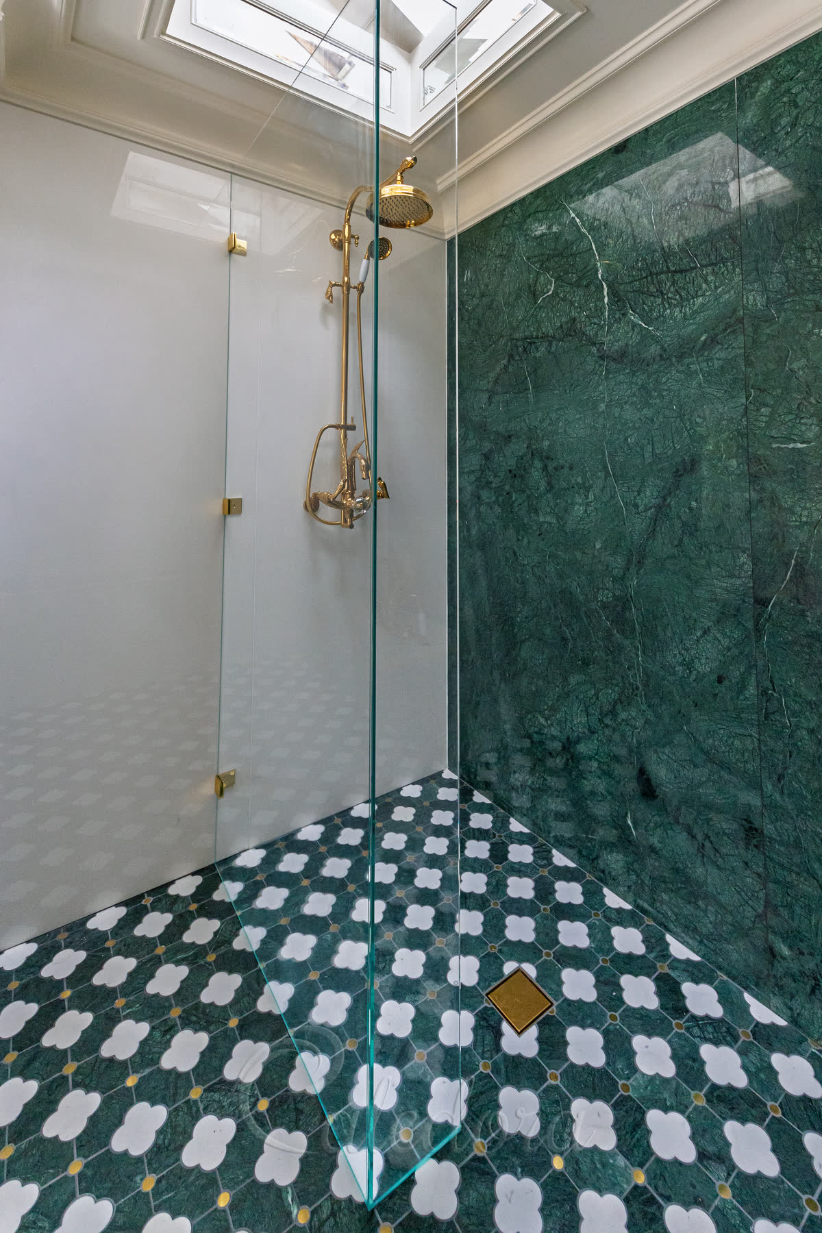 Shower screen with return panel from inside shower showing L-shaped configuration with ultra clear glass and polished brass fittings