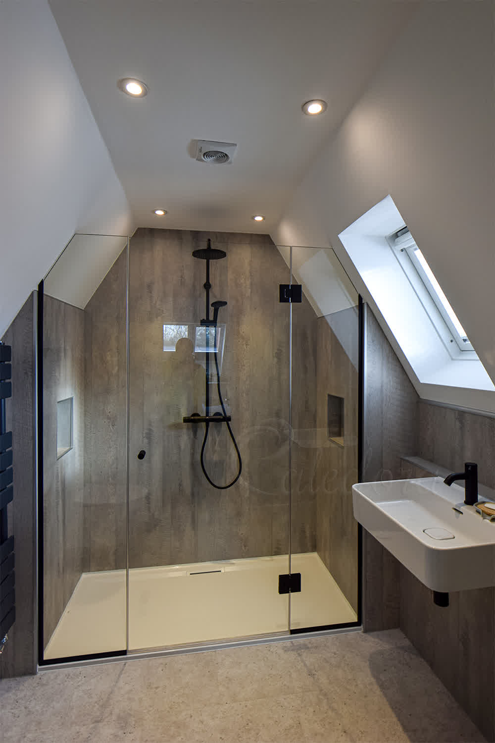 Frameless inline shower door installed under slanted ceiling in loft bathroom