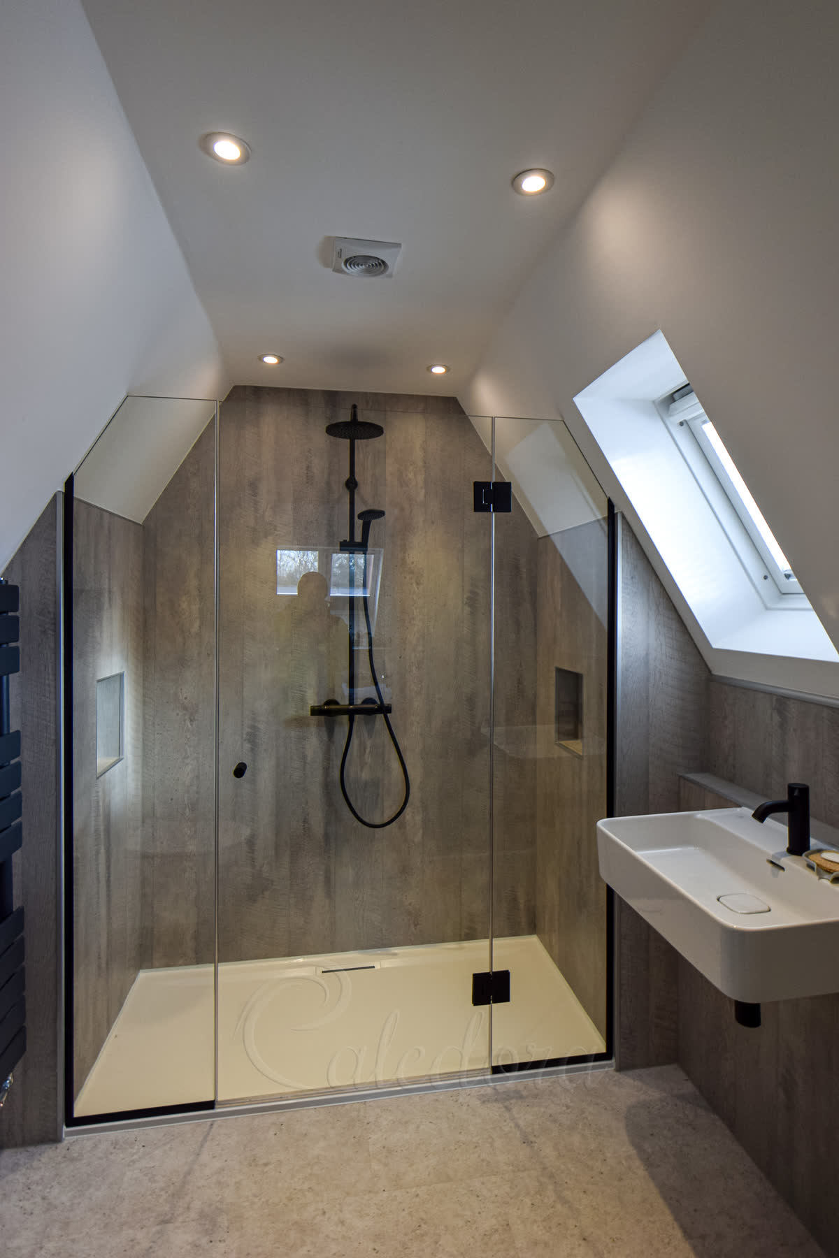 Frameless inline shower door installed under slanted ceiling in loft bathroom
