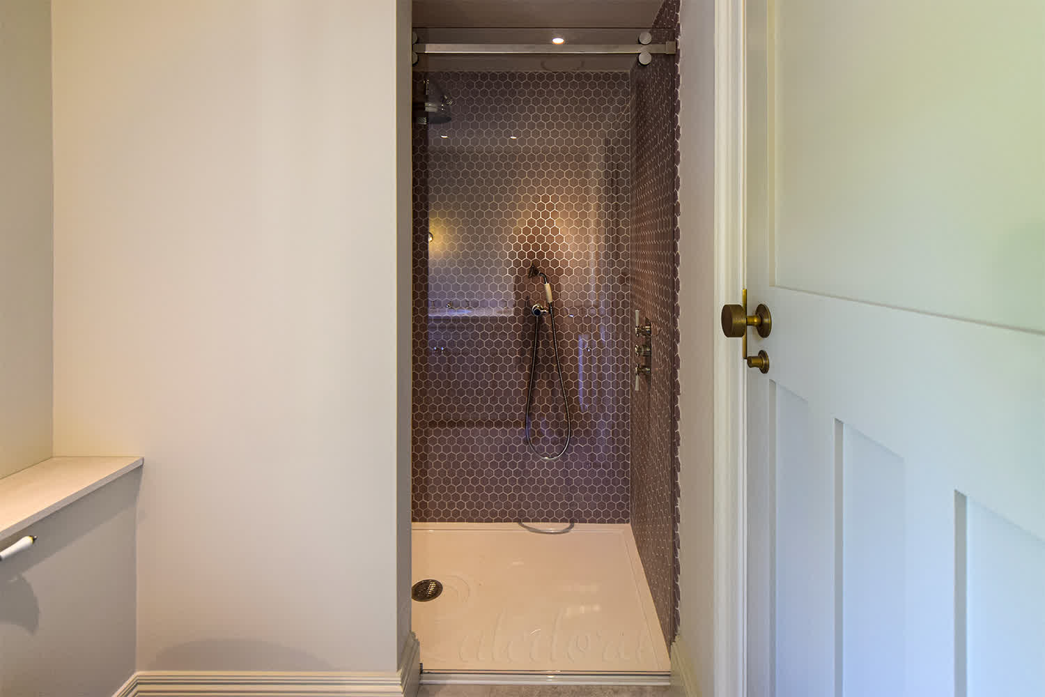 Sliding glass door in closed position showing track system and hexagonal bronze-copper wall tiles