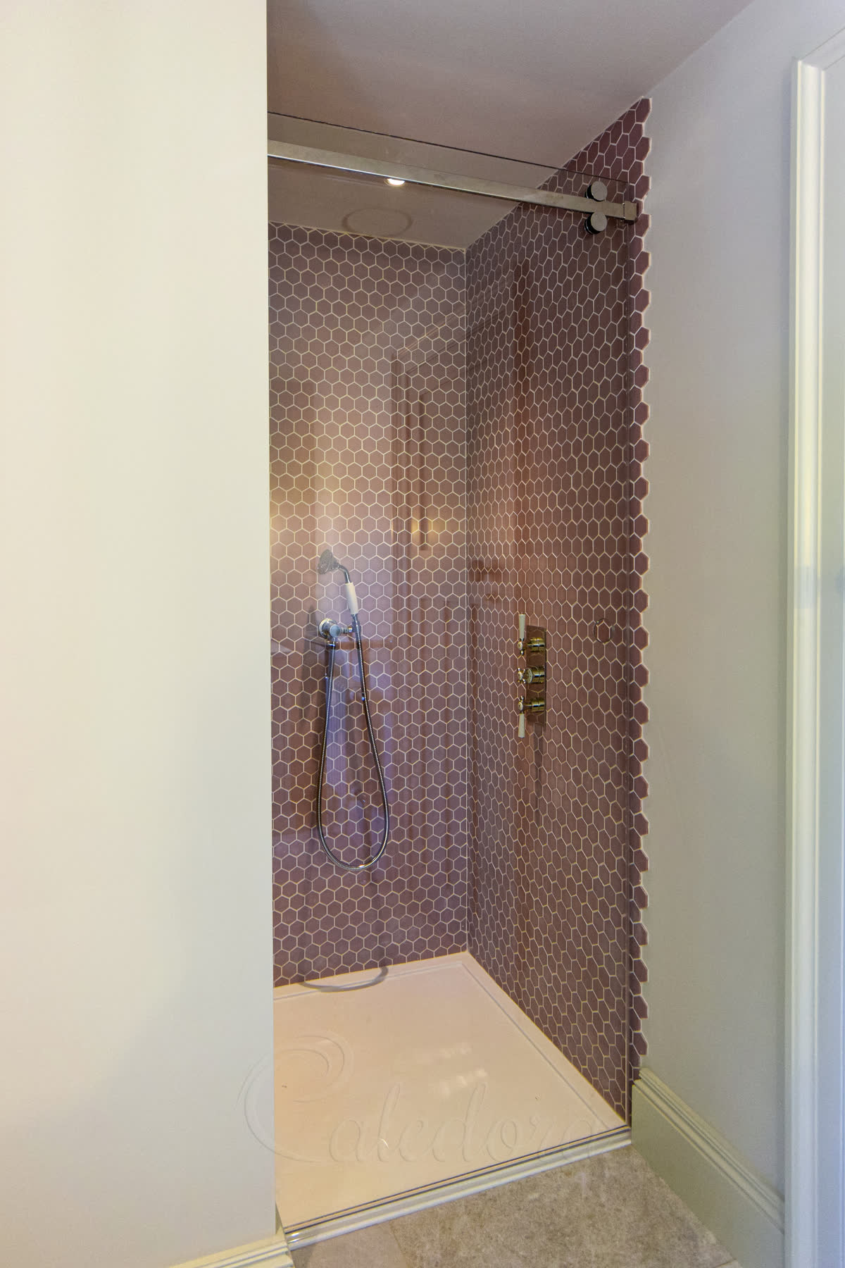 Sliding glass door in closed position showing track system and hexagonal bronze-copper wall tiles