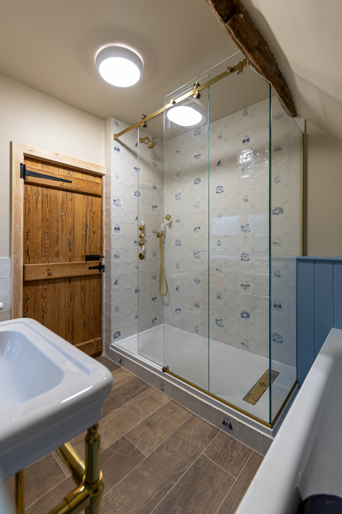 Partially open sliding shower door with brass fittings matching traditional bathroom style