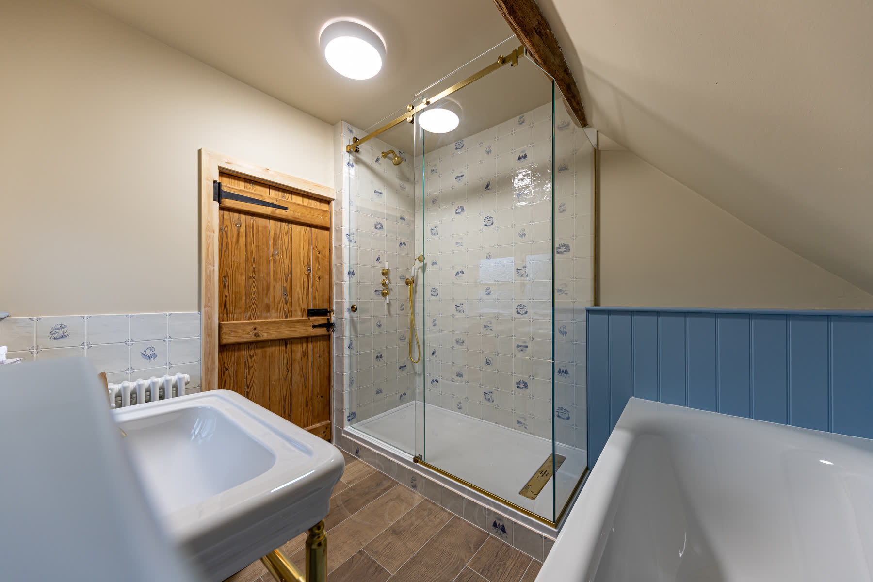 Horizontal view of the sliding door shower enclosure showing brass track system and exposed ceiling beam