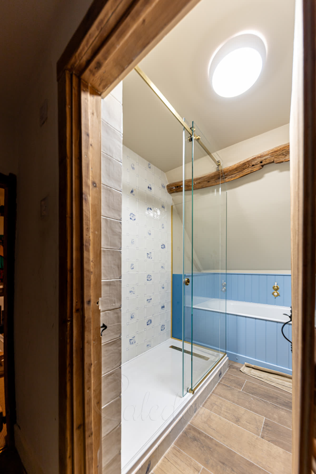 View through doorway of custom shower enclosure with painted glass edge matching blue half-wall