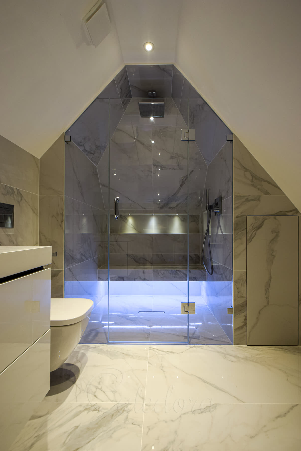 Side view of custom frameless shower door with chrome hinges perfectly fitted to sloped ceiling