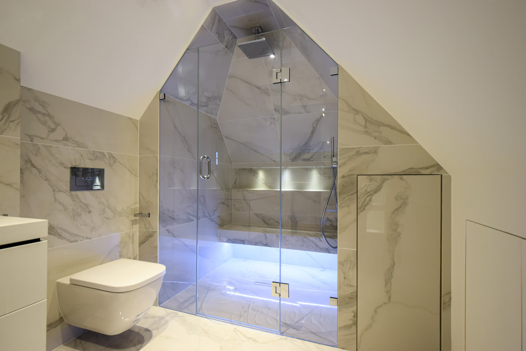 Wide view of the frameless shower enclosure showing the complete installation with sloped ceiling
