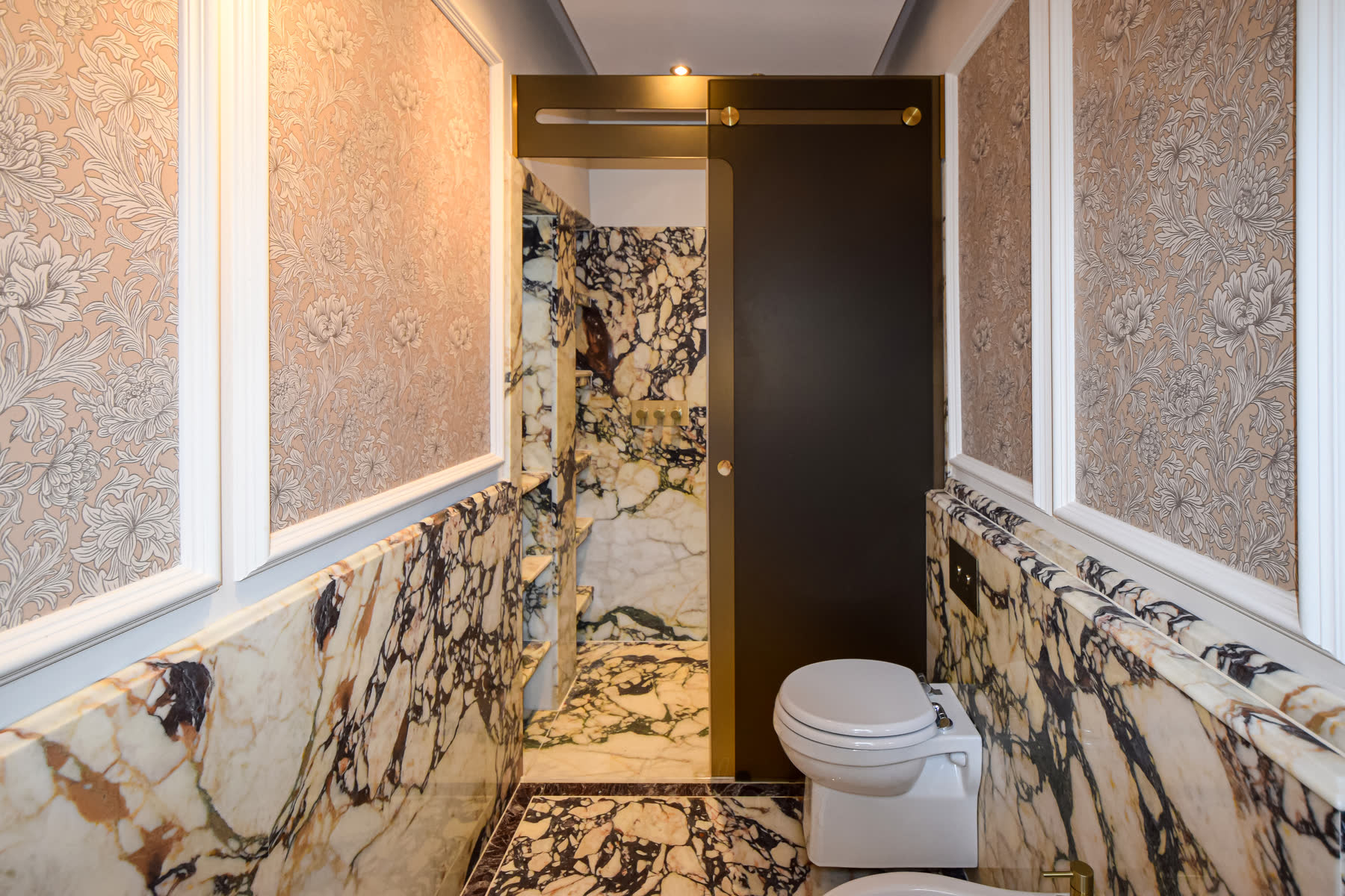 Smoked glass shower enclosure with trackless sliding door system and brass-coated stainless steel hardware