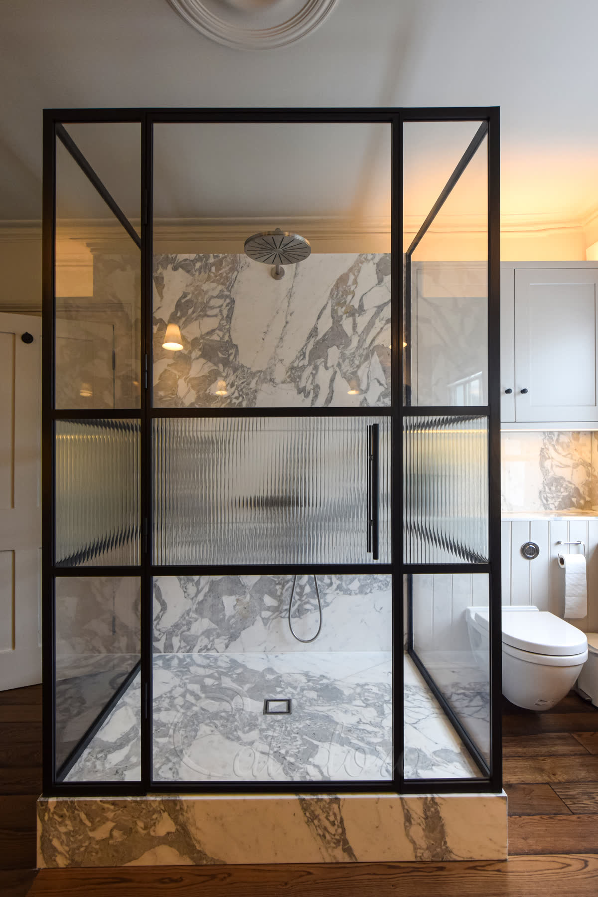 Front view of three-sided shower enclosure with black grid frames and hinged door with fluted glass insert