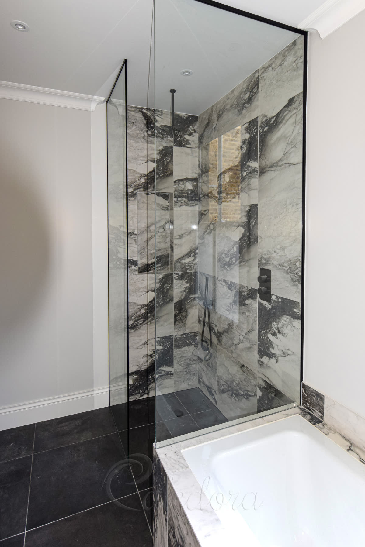 Two frameless shower screens creating a corner shower entry next to white bathtub
