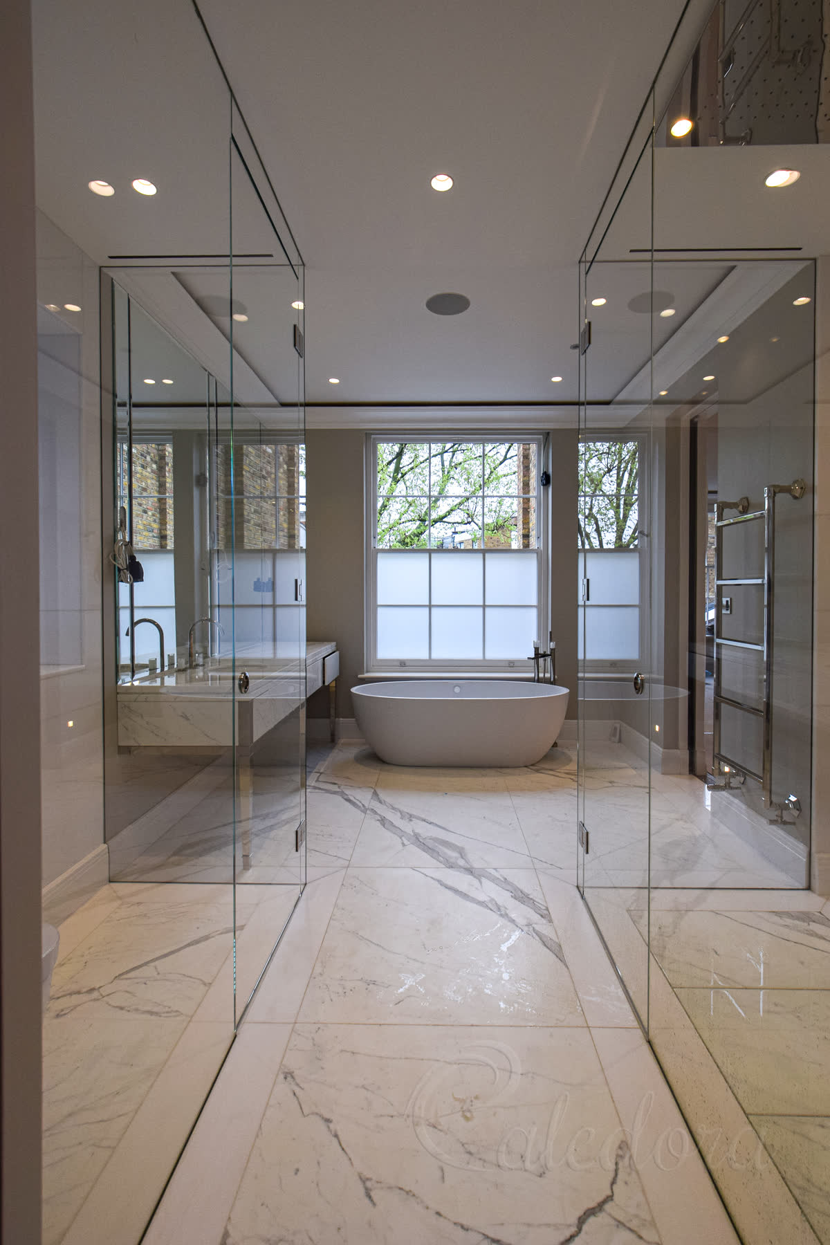 Frameless design with glass panels recessed into walls, ceiling and floor for clean appearance in London bathroom