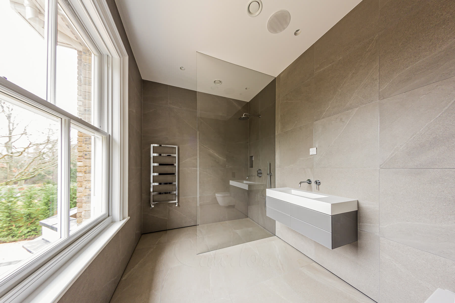 Complete bathroom view showing frameless walk-in shower glass panel with wall recessed installation and grey marble tiles
