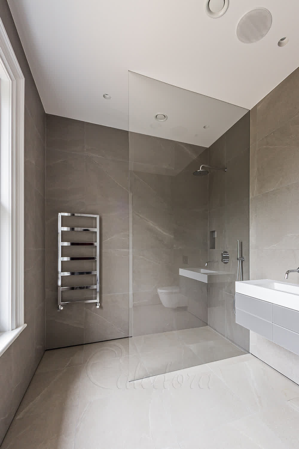 Walk-in shower glass panel recessed into wall and ceiling grooves with no visible metal fixings in modern bathroom
