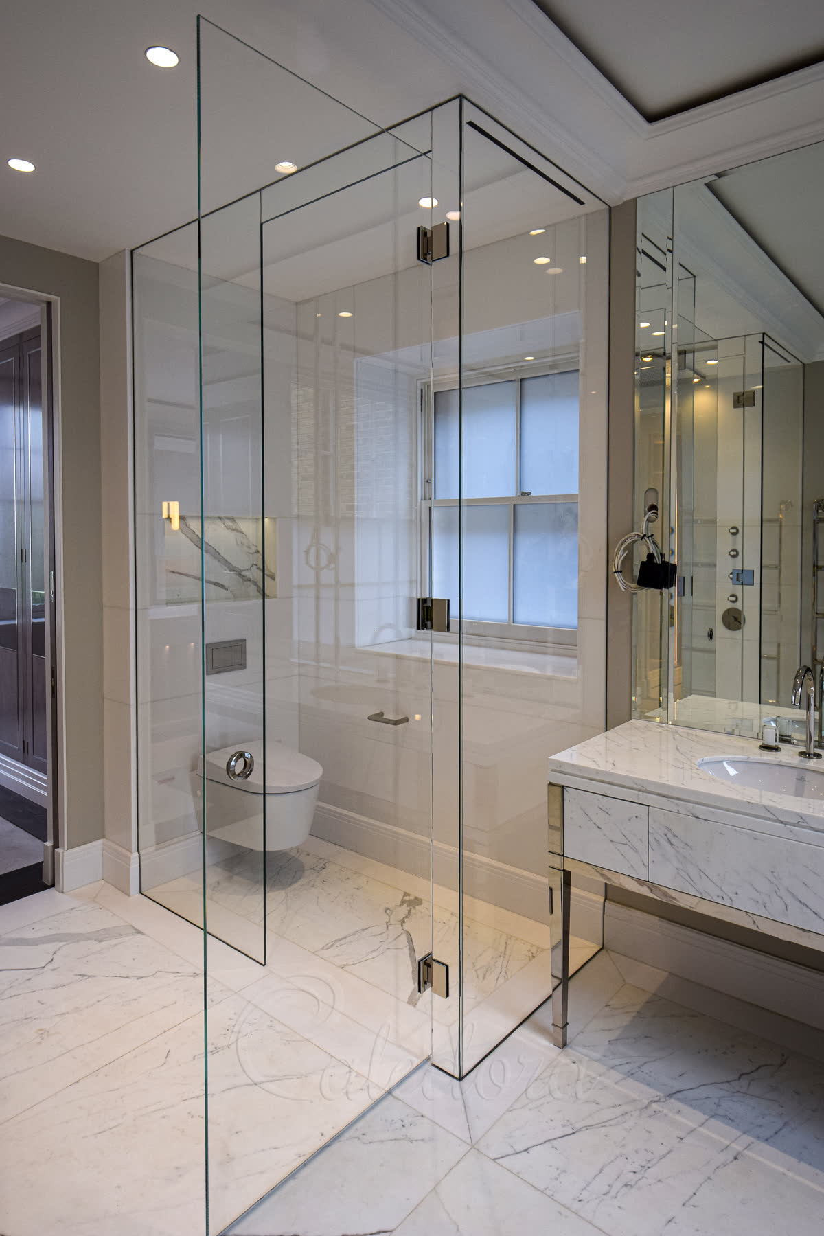Full-height glass with ceiling extraction grilles drawing air through long slot vents above the wet room shower