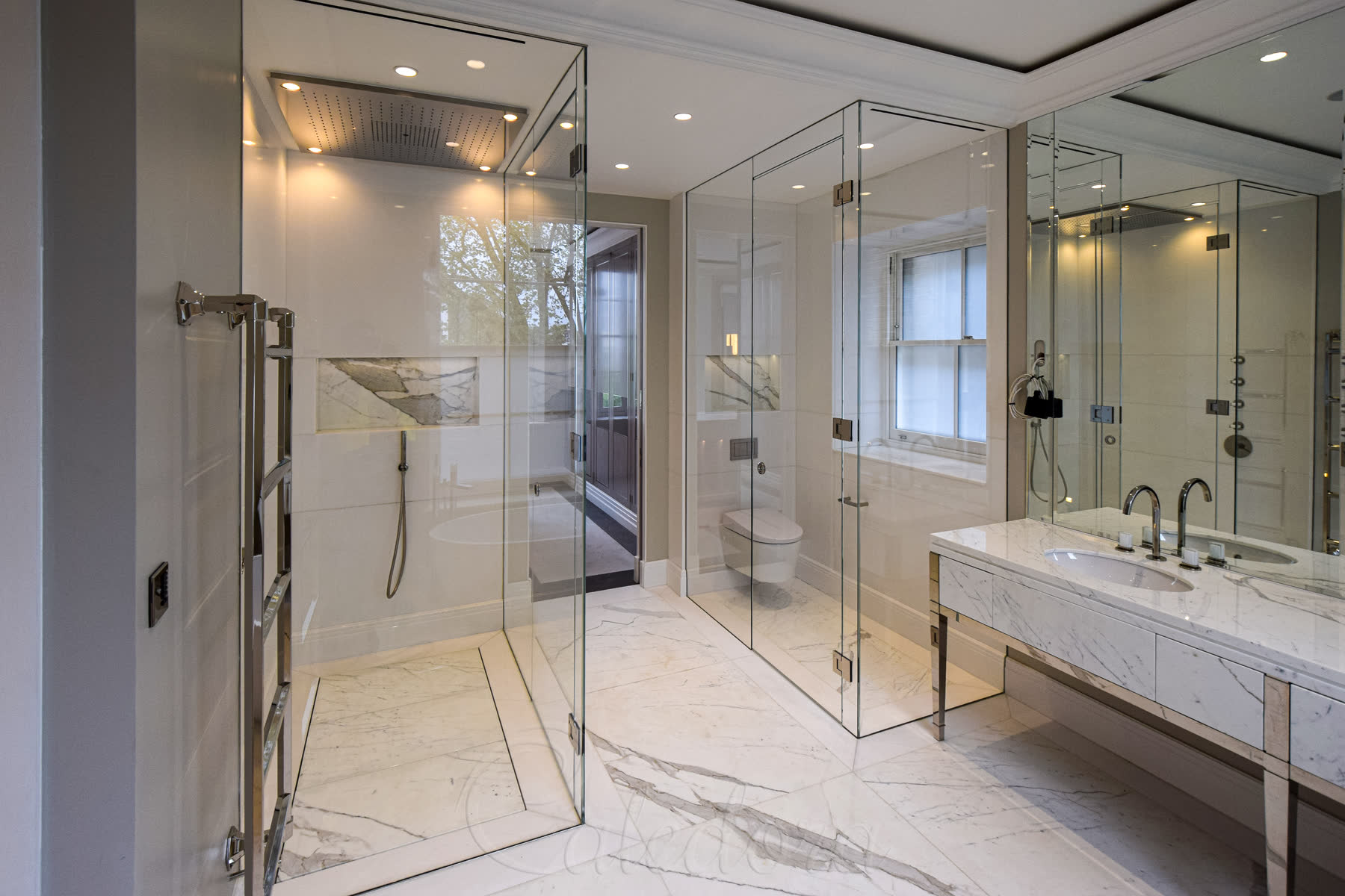 Ceiling-mounted rainfall head spanning the full width of the wet room shower enclosure in the London bathroom