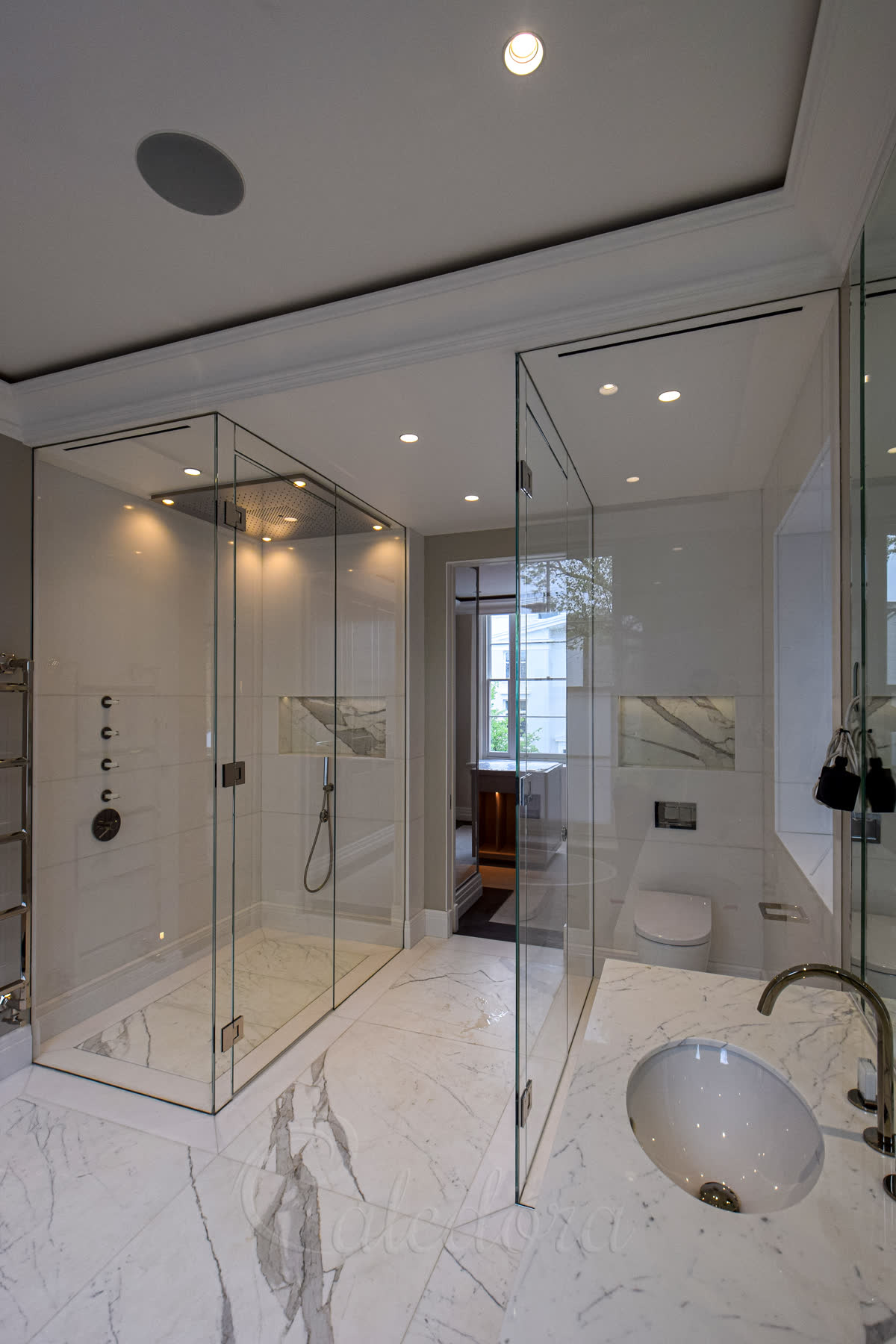 Frameless wet room shower enclosure in luxury London bathroom with hidden drain marble floor and matching WC enclosure