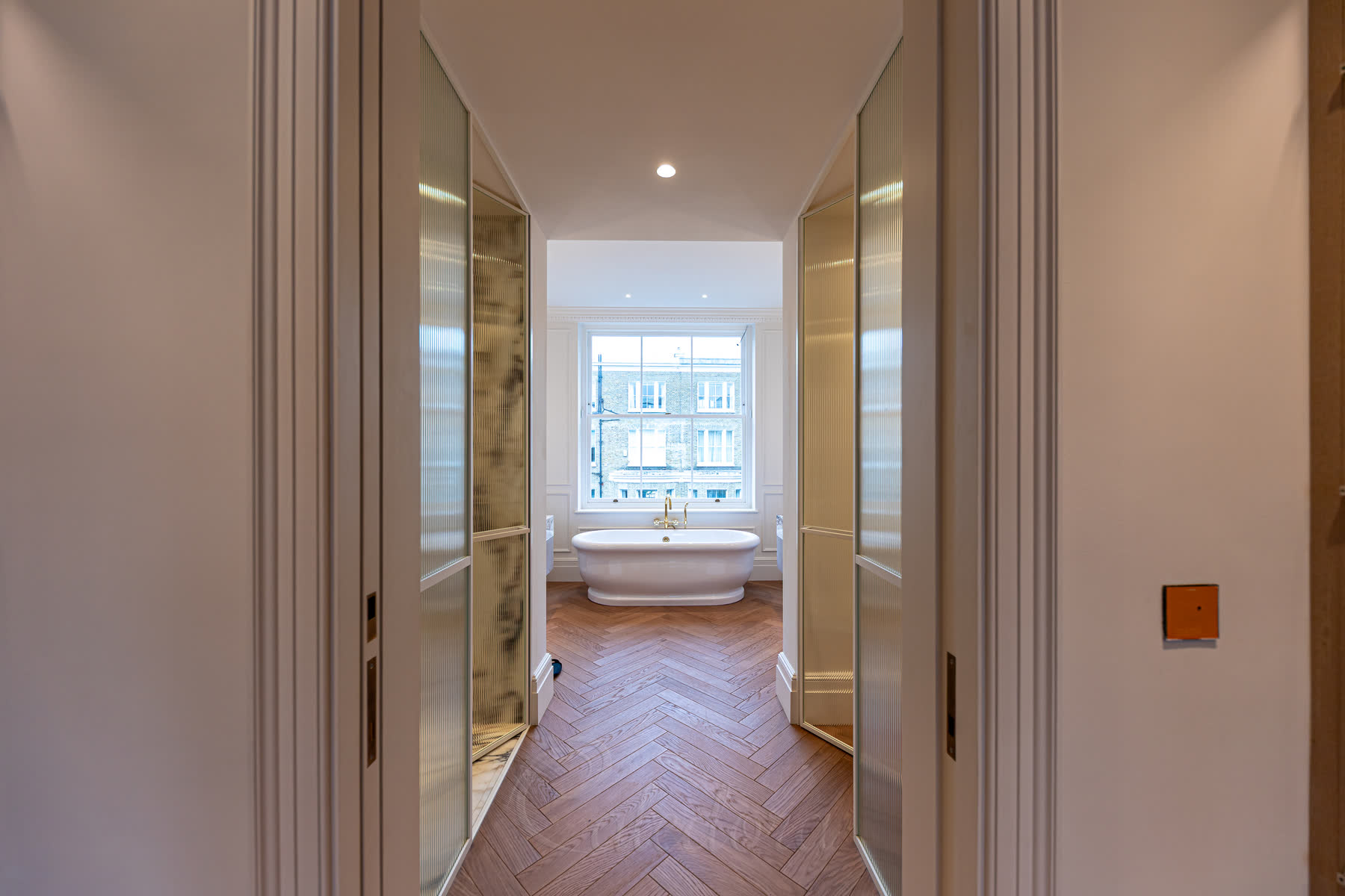 White shower doors both opened inward showing flexible corridor design with fluted glass