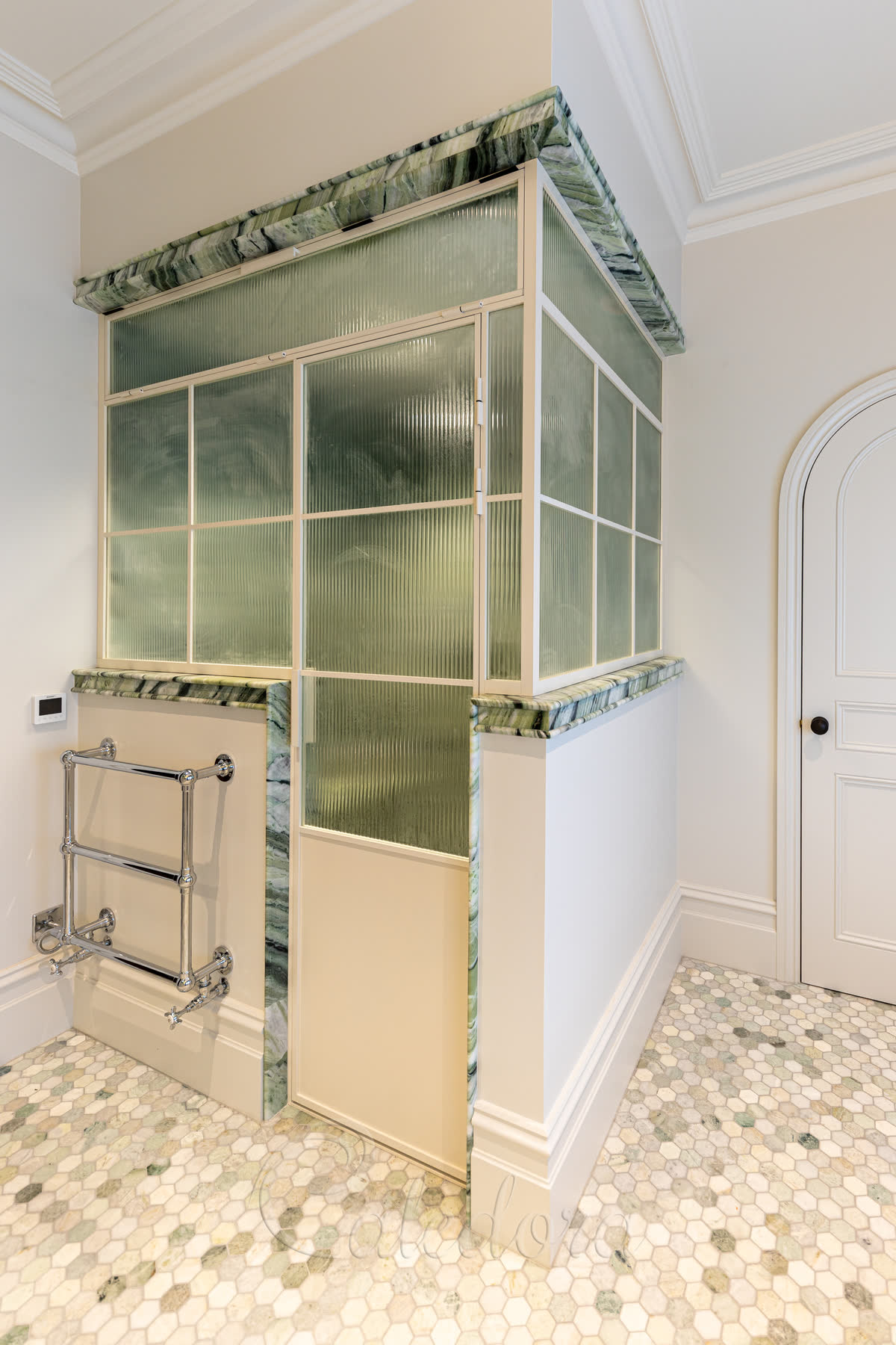 Steam shower enclosure with white powder-coated frame and fluted glass panels in a modern bathroom with marble details