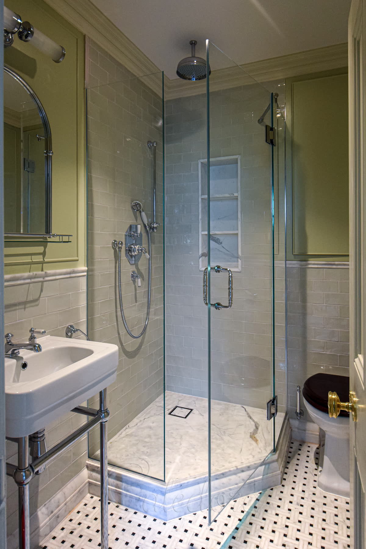 Polished chrome pentagon shower enclosure with 135° frameless hinges and a reinforcement arm — 10mm ultra clear glass on a marble base, fitted between a toilet and basin in a compact corner