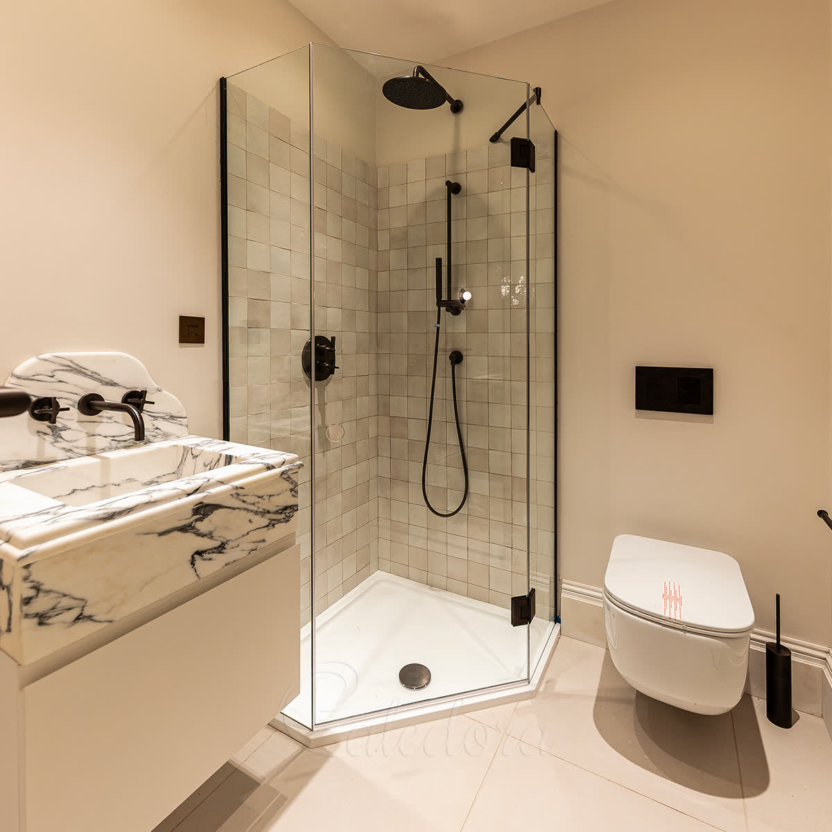 Frameless pentagon shower enclosure with matte black hinges and shower fixtures — soft grey square tile inside the enclosure, two fixed glass screens meeting the hinged door at 135° each to form the pentagon shape