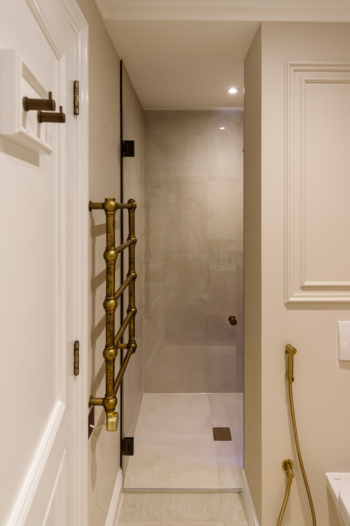 Frameless traditional shower door with antique brass hinges and doorknob