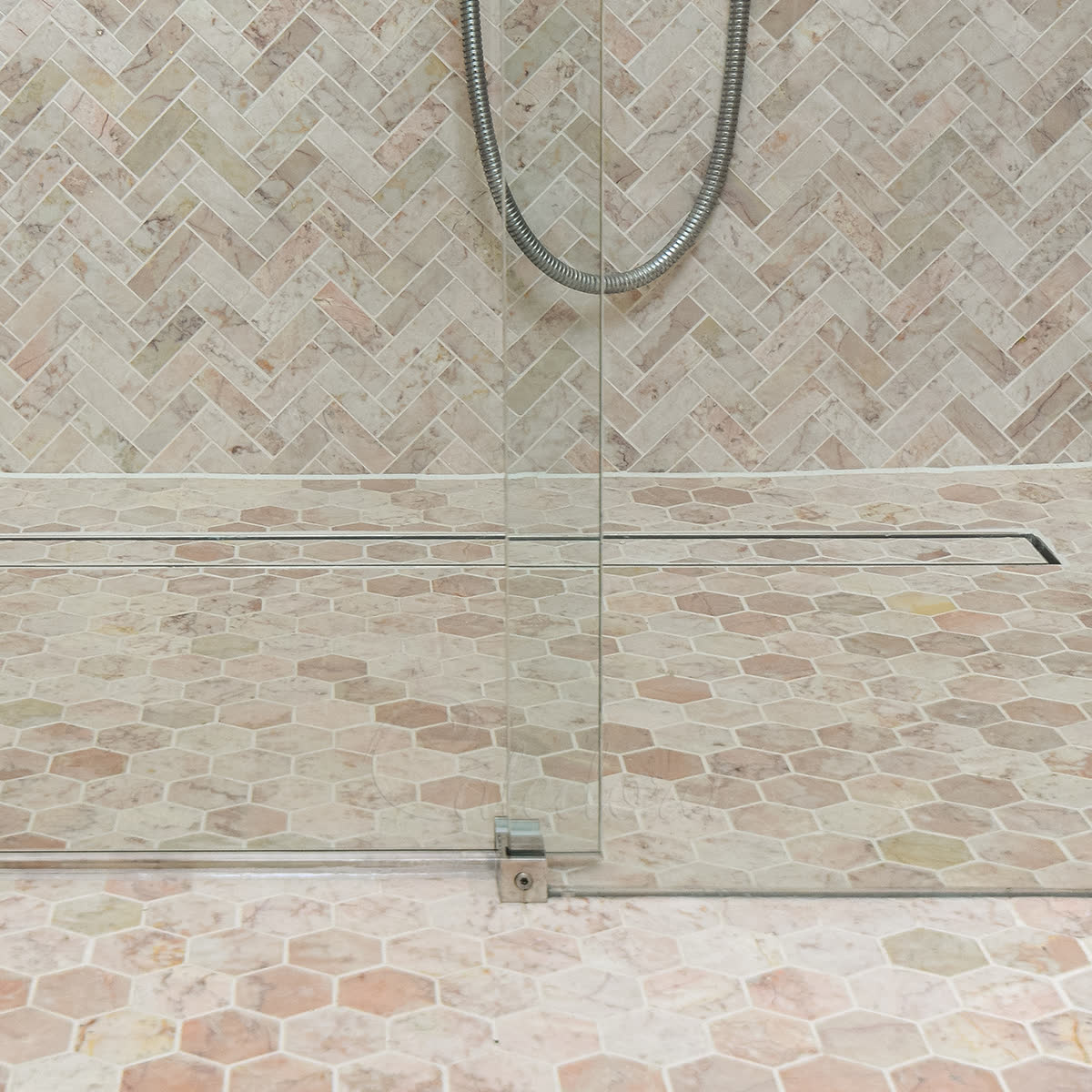 Close-up of the glass-to-glass panel overlap on a frameless sliding shower door — the sliding door slides past the fixed panel, routing water through the overlap rather than against a vertical seal