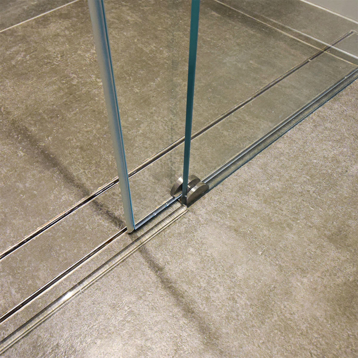 Sliding shower door bottom edge tracking through a small floor guide screwed to the tray