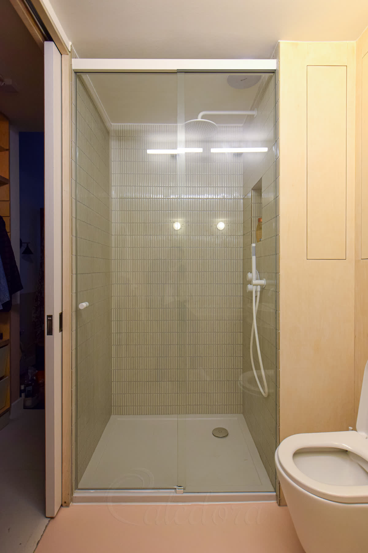 Frameless sliding shower door with white track system in a modern bathroom setting
