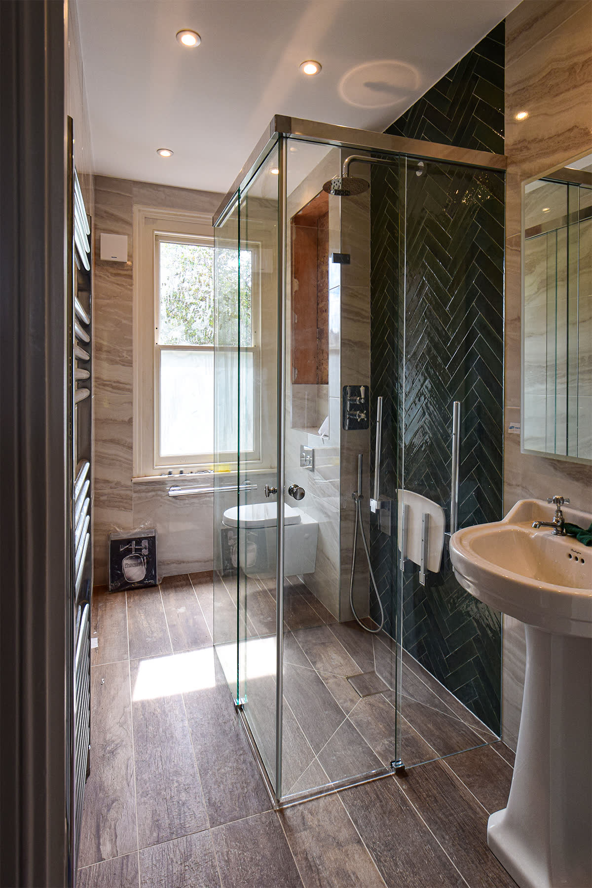 Three-sided shower enclosure with corner double sliding doors — chosen because a toilet, a basin and a narrow passage to the back of the room each blocked a hinged swing on the three available walls