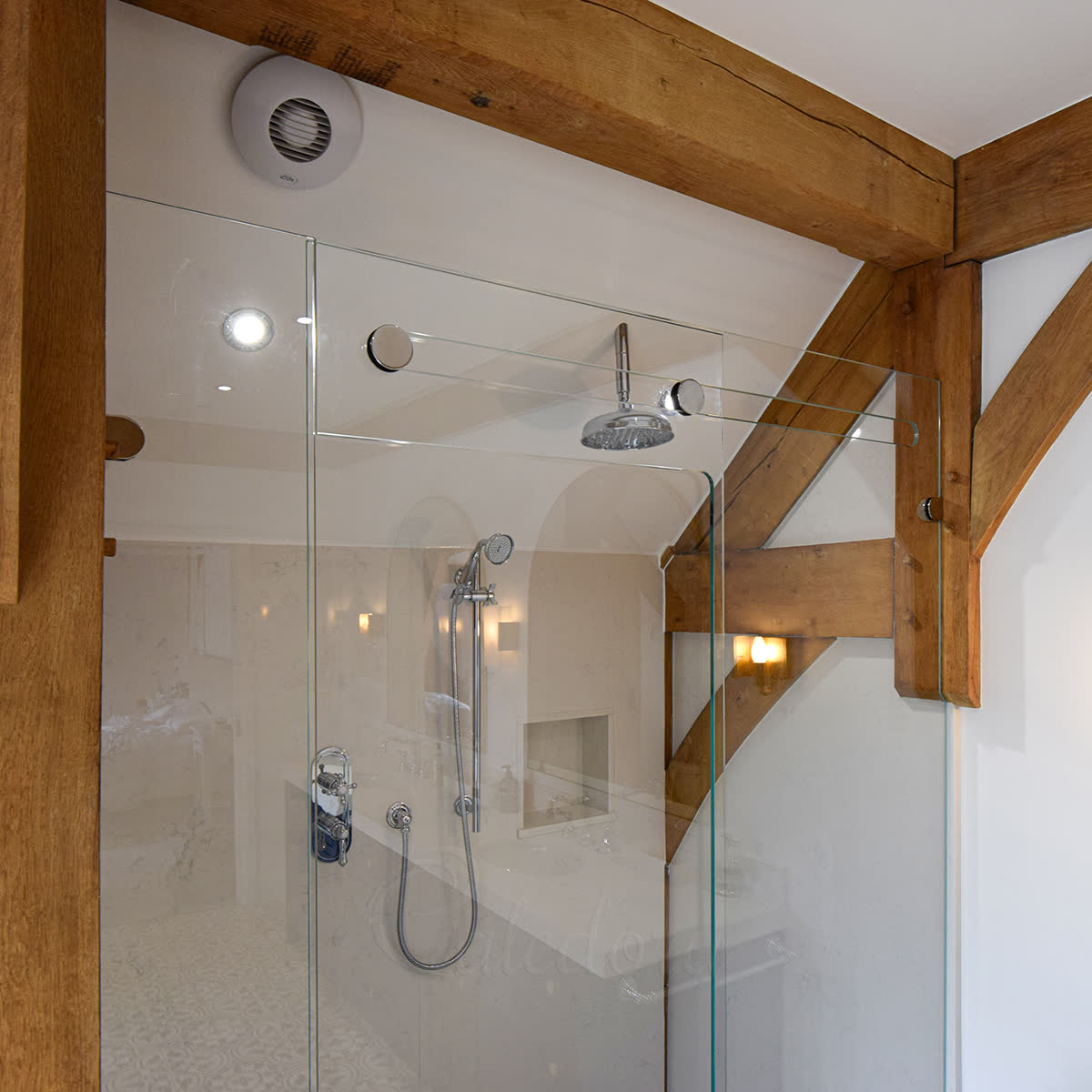 Close-up of stainless-steel wheels running inside a notch cut into the fixed glass panel — the trackless sliding mechanism in a Basingstoke install