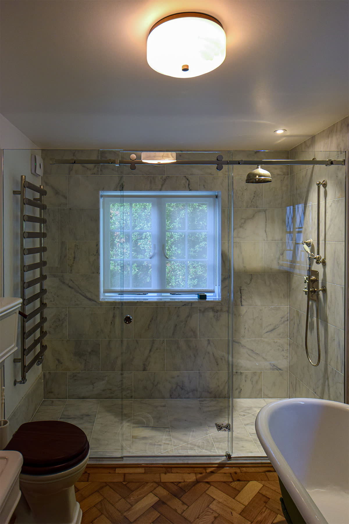 Wall-to-wall sliding shower door across a 2,500 mm opening with an 800 mm sliding door centred between two fixed panels — a width a hinged door could not carry without straining its pivots