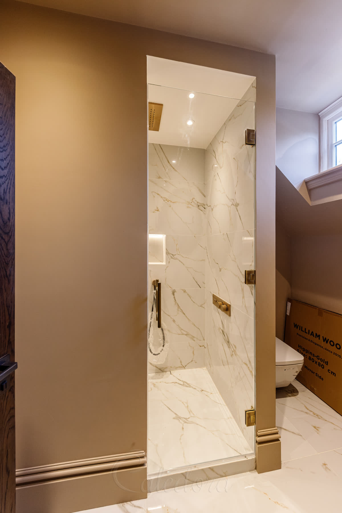 Frameless hinged shower door with three antique brass hinges, 150mm air vent above, swing both ways design in marble ensuite bathroom